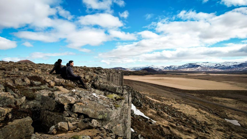 Gerduberg Cliffs acantilado en islandia, dos personas sentadas arriba del acantilado mirando el horizonte