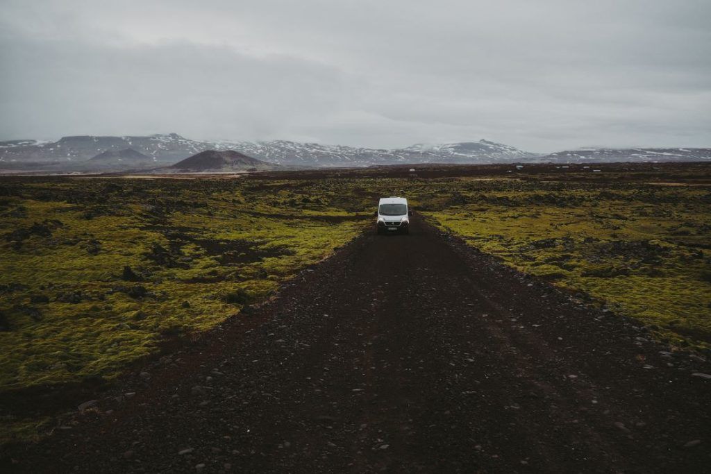 vistas de carretera de tierra en islandia con una autocaravana en el camino y montañas de fondo