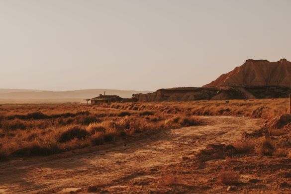 paisaje desértico al atardecer y casa abandonada al fondo