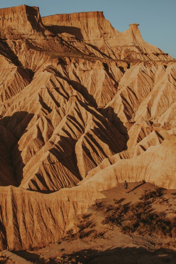 paisaje desértico al atardecer, montañas deserticas y persona a mano derecha que se ve al fondo que camina hacia las montañas