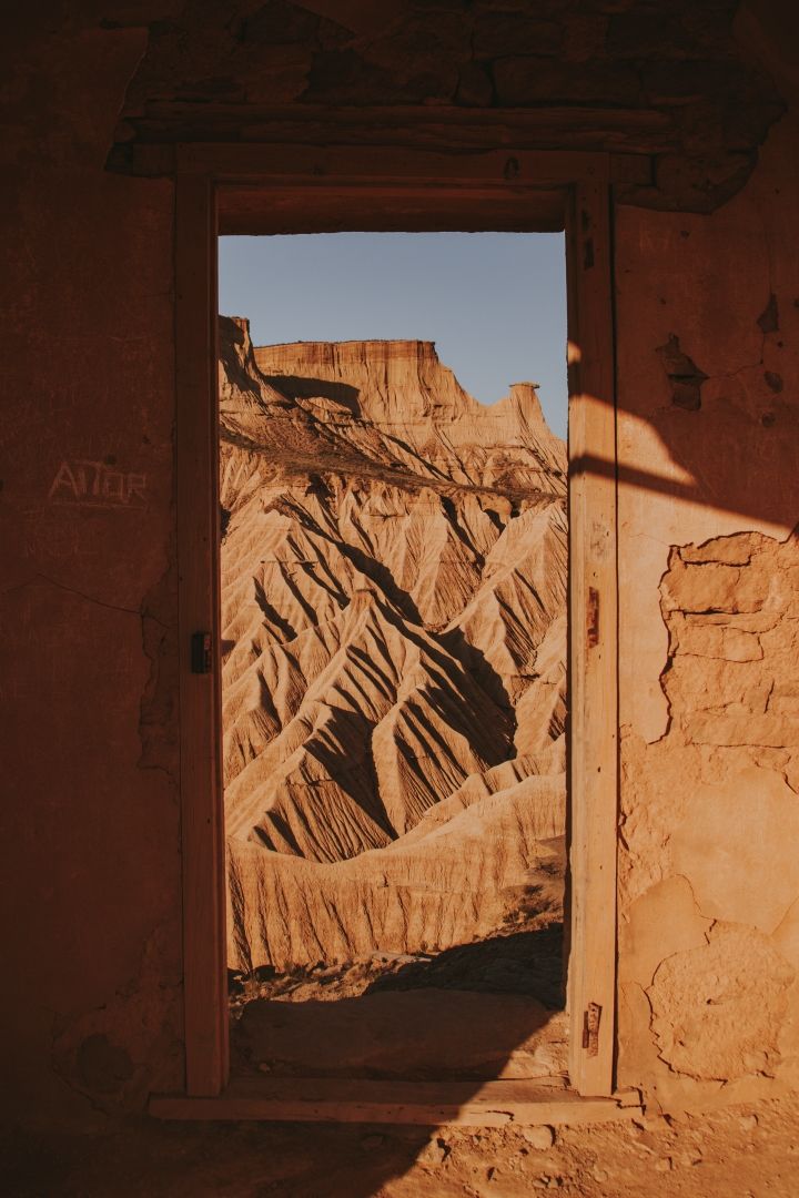 marco de puerta abandonada y dentro de el se ven montañas deserticas