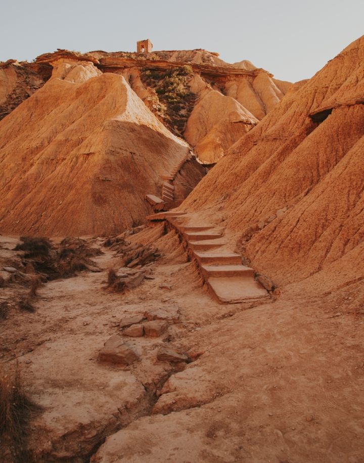 montaña desertica con puerta arriba de ella y escaleras que suben hasta allí abandonadas