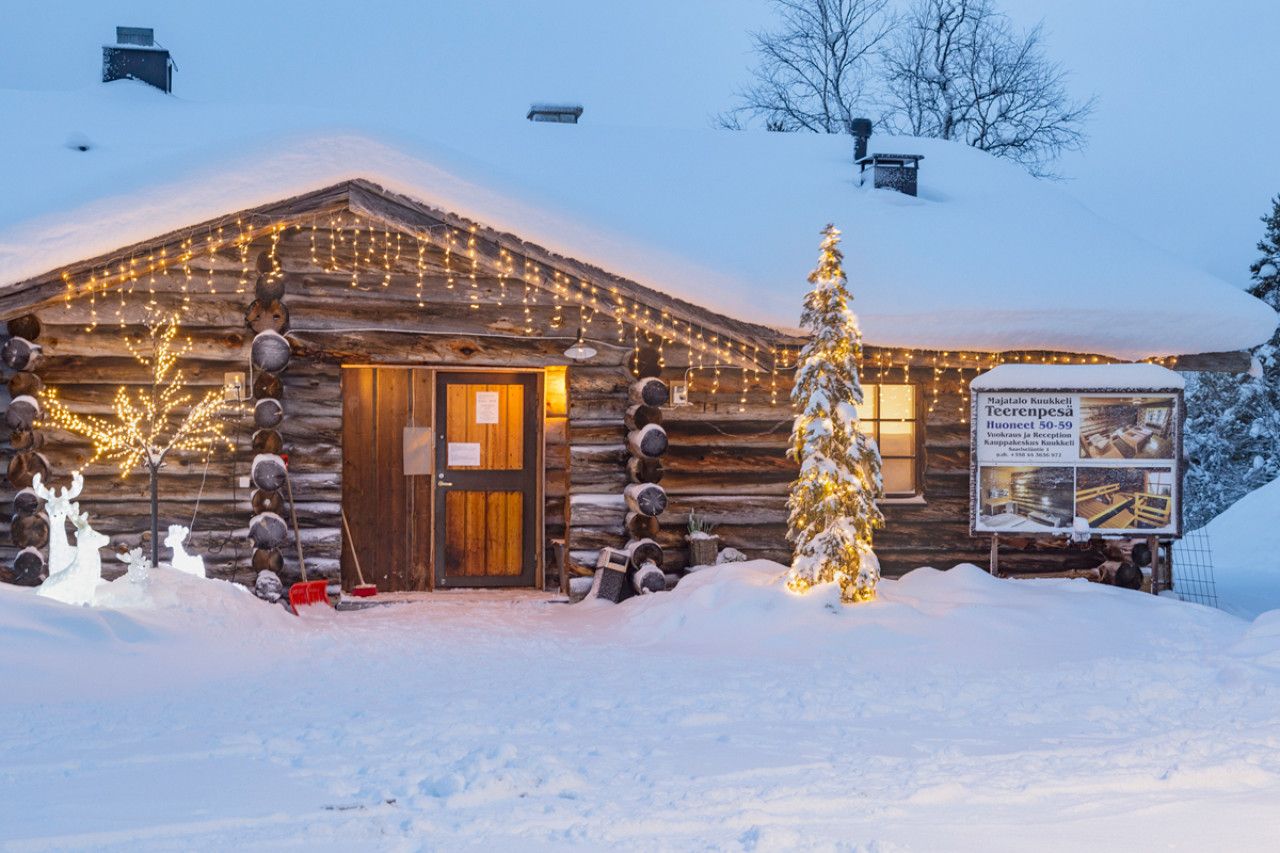 auroras-boreales-finlandia cabaña de madera iluminada cubierta de nieve en laponia