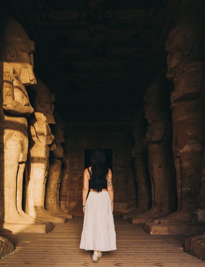 chica de espaldas caminando dentro de un templo egipcio