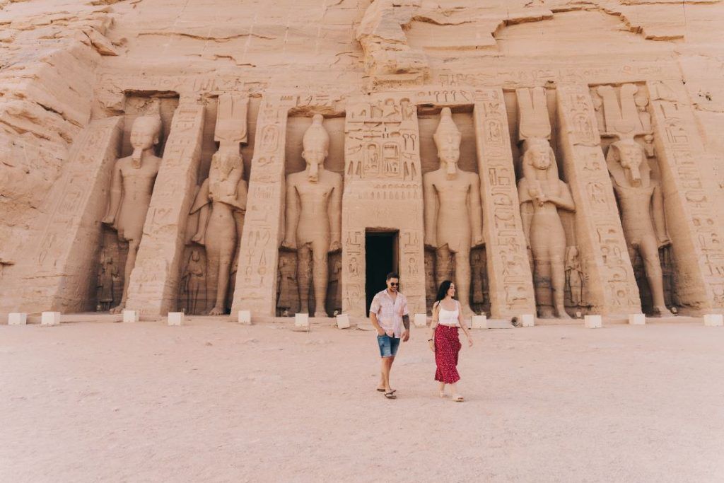 chico y chica caminando sonriendo y detras un templo egipcio