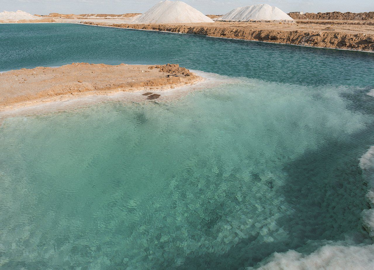 agua de mar turquesa y transparente rodeado de montañas de sal