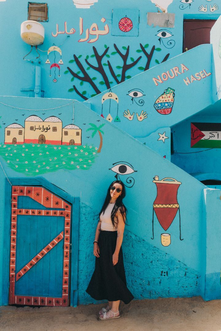 chica posando y mirando a la cámara apoyada en una pared pintada de dibujos y color azul eléctrico