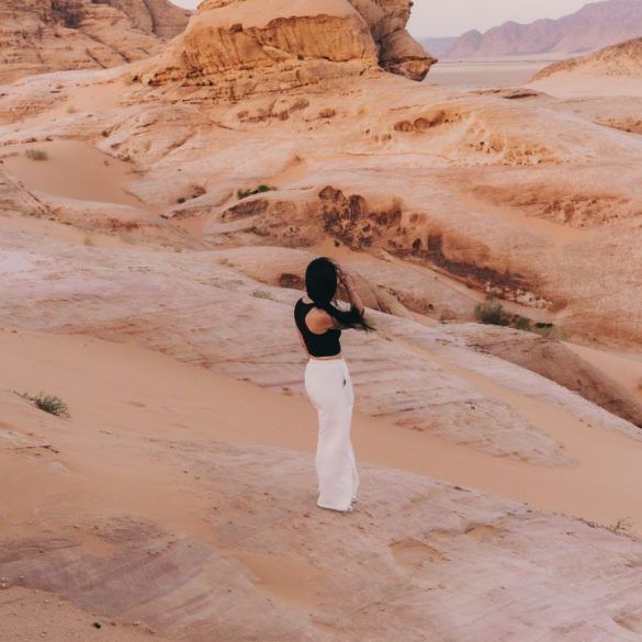 chica de espaldas en un paisaje de arena y piedras rojizas