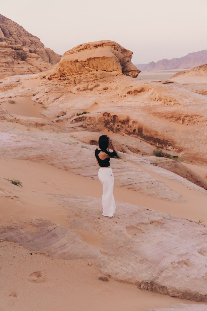 chica de espaldas mirando hacia el desierto que le rodea de piedra y arena rojiza