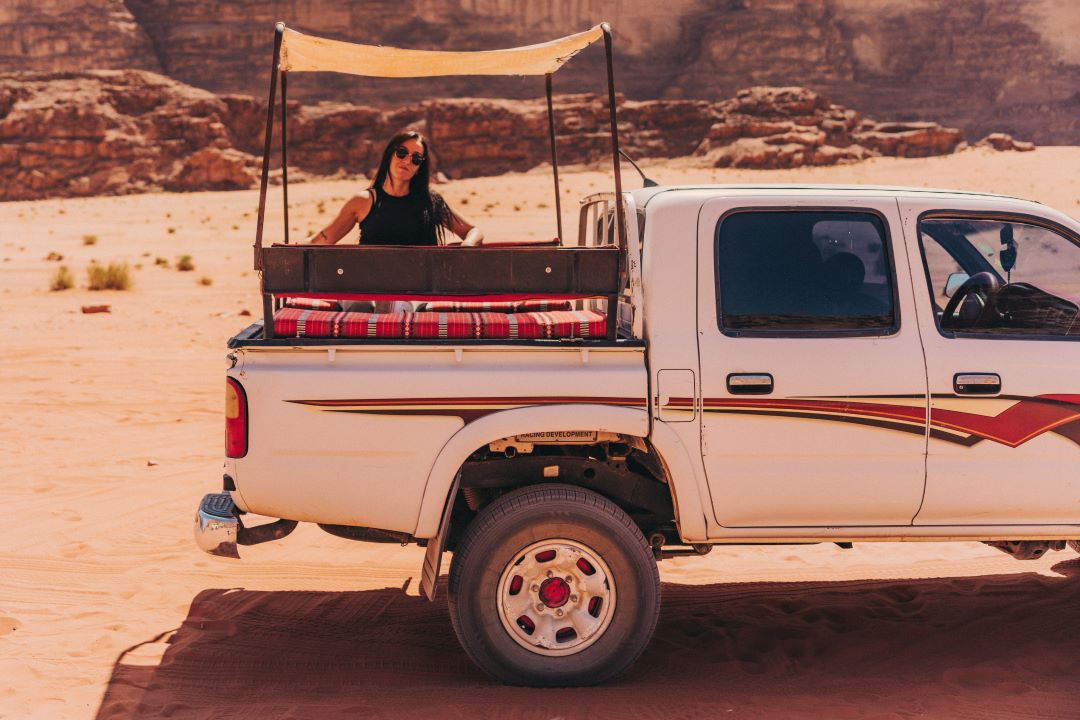 chica subida en un jeep detras mirando hacia la cámara sentada en un paisaje de desierto
