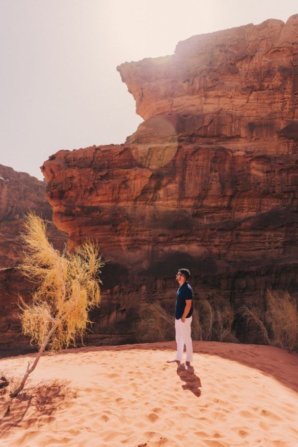 chico mirando a la cámara posando en un desierto de arena y montañas de piedra