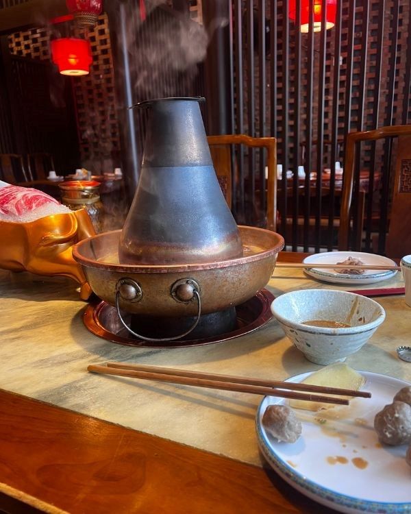 mesa de restaurante con caldero y platos con palillo chinos
