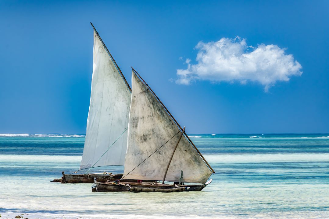 barcos de vela navegando hacia la derecha en mar de arena blanca
